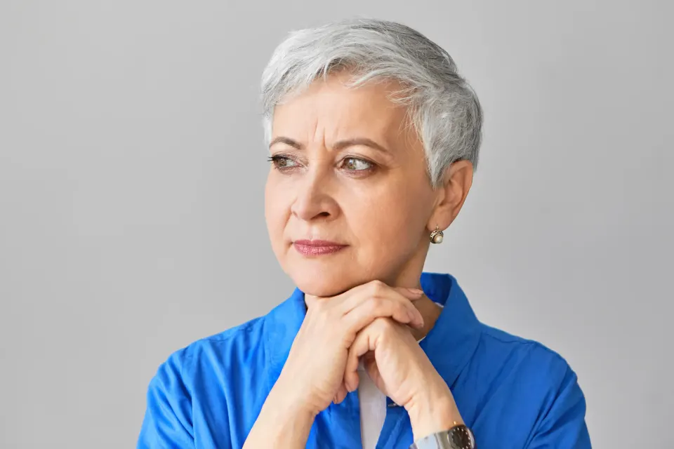 Woman in her 40s smiling in soft natural light, examining gentle expression lines around her eyes